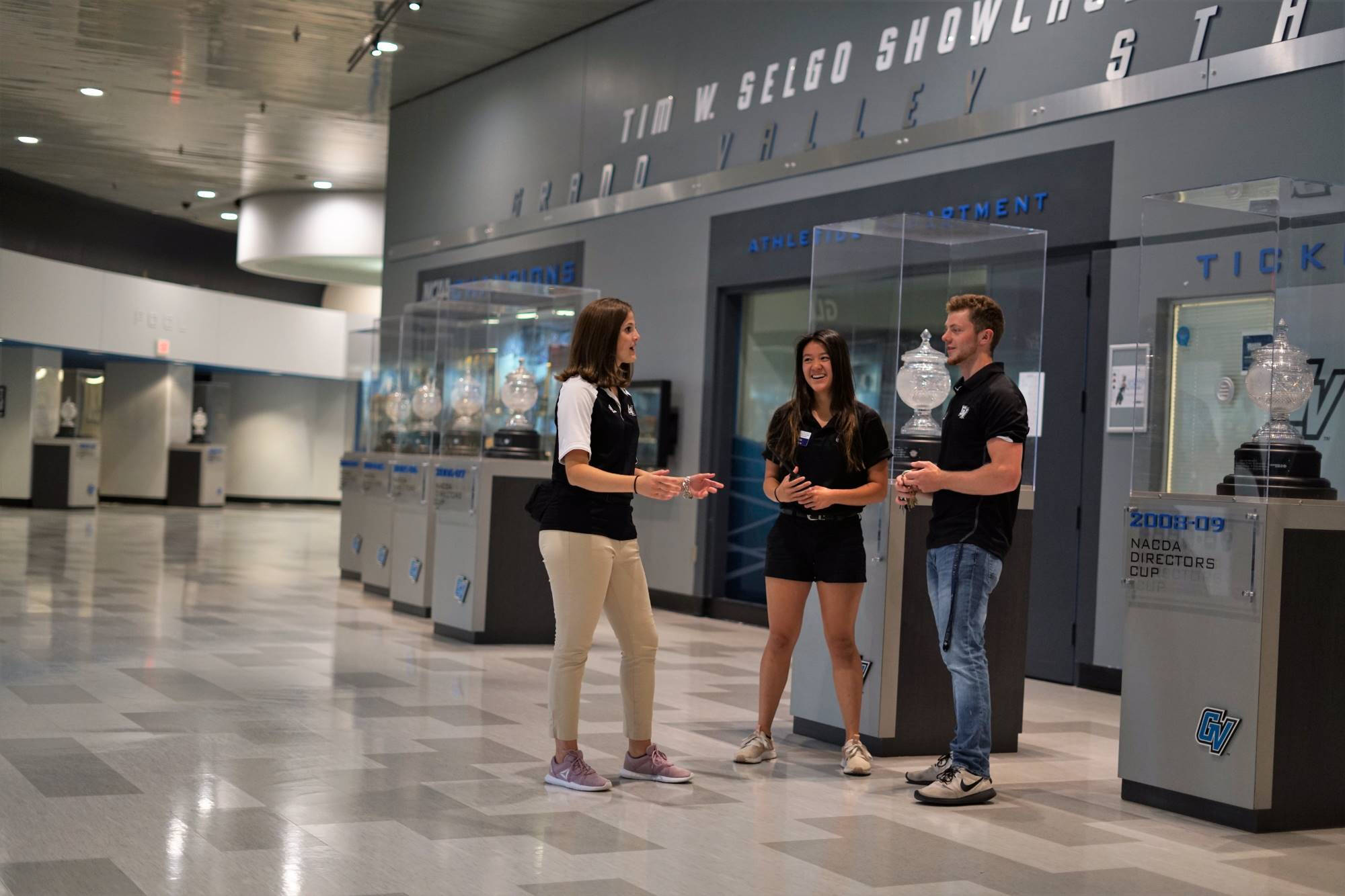 three individuals standing outside of a trophy case talking